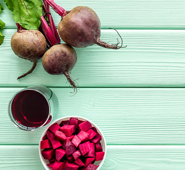 raw beets and beet juice on wood background
